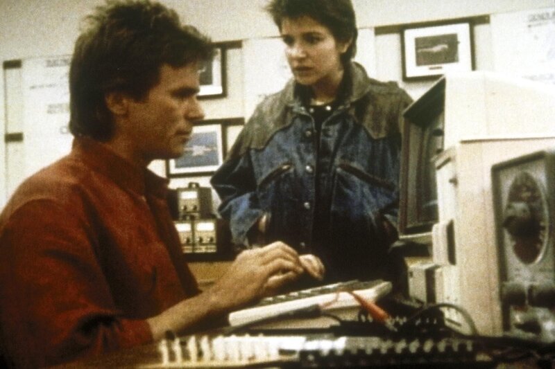 MacGyver (Richard Dean Anderson, l.) macht die Probe aufs Exempel. Kate (Darcy Marta, r.) beobachtet ihn. – Bild: Paramount Pictures