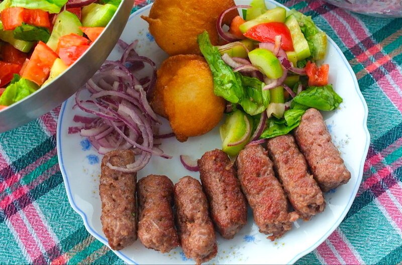 In Montenegro werden Ćevapi mit Krapfen und buntem Salat serviert. – Bild: Elephant Doc