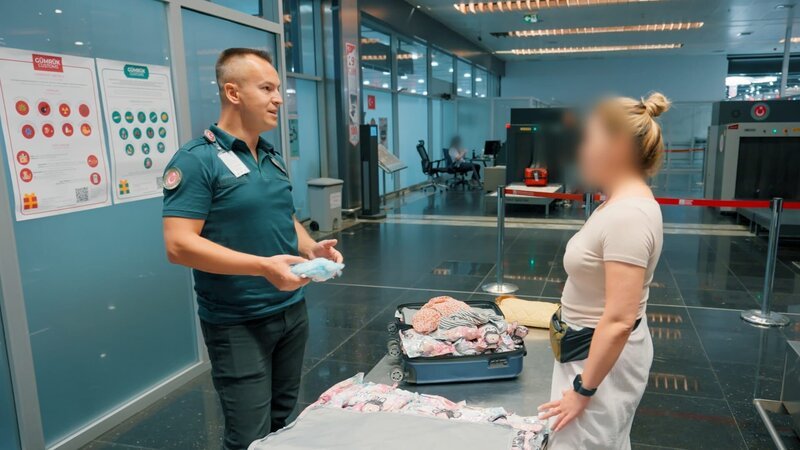 Food items belonging to a Doha passenger are confiscated. Mangoes are found on a passenger from Senegal. Electronic devices are discovered on a Kyrgyz passenger. – Bild: Warner Bros. Discovery