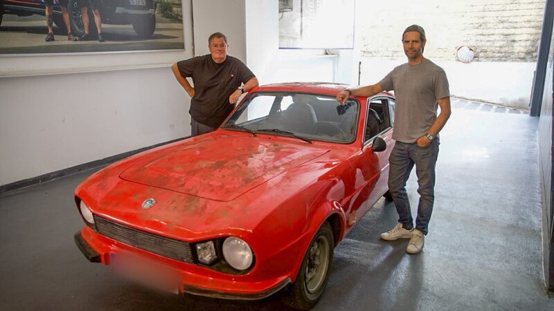 Mike on left side of beaten up red Anadol, arm resting on car, Elvis on right hand of car, arm resting on car – Bild: Warner Bros. Discovery