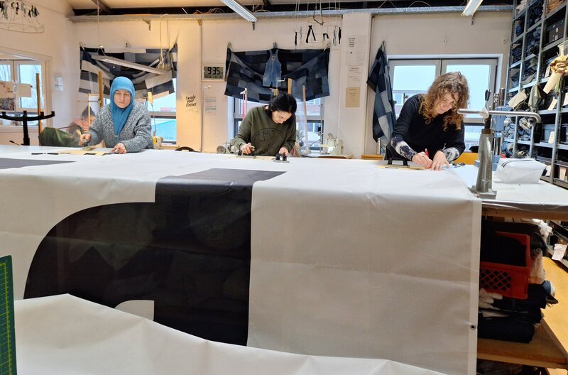 Eben hingen diese metergroßen Banner noch bei der Handball- Europameisterschaft in Düsseldorf. Jetzt schneidert das Team von „Bridge&Tunnel“ in Hamburg-Wilhelmsburg daraus 500 Kulturbeutel. Die Zeit ist eng: Denn die Kulturtaschen sollen schon eine Woche später zum Finale in Köln verschenkt werden. – Bild: NDR/DHF Eben hingen diese metergroßen Banner noch bei der Handball- Europameisterschaft in Düsseldorf. Jetzt schneidert das Team von „Bridge&Tunnel“ in Hamburg-Wilhelmsburg daraus 500 Kulturbeutel. Die Zeit ist eng: Denn die Kulturtaschen sollen schon eine Woche später zum Finale in Köln verschenkt werden. – Bild: NDR/DHF