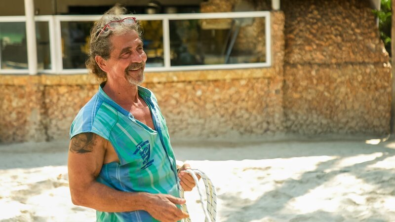 Heino smiling on the volleyball court of Soul Breeze during mast repairs – Bild: Warner Bros. Discovery