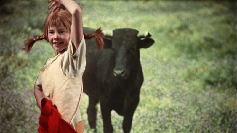 Mit einer Torero-Einlage gelingt es Pippi (Inger Nilsson), den Stier müde zu machen, bevor er dem kleinen Nisse etwas antun kann. – Bild: Studio 100 Media