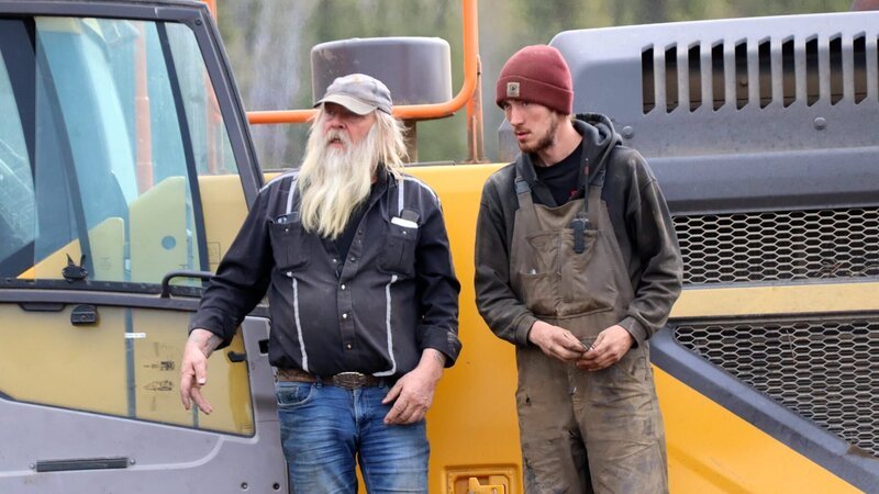 Tony Beets and Jacob Flood stood on side of excavator on tracks – Bild: Warner Bros. Discovery