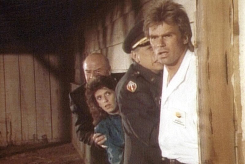 (v.l.n.r.) Thornton (Dana Elcar), Carrie (Mary Beth Barber), General Makepeace (Jack Colvin) und MacGyver (Richard Dean Anderson) beobachten eine Schießerei. – Bild: Paramount Pictures