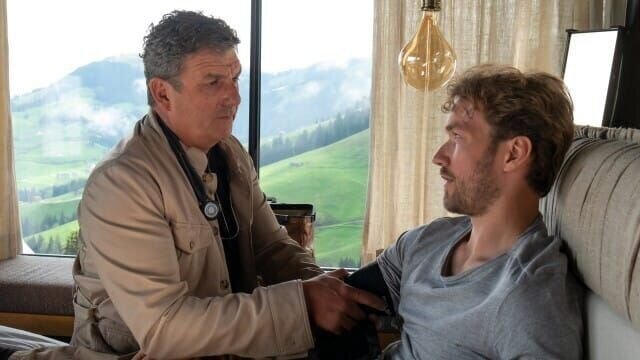 Nach seinen Ausfallerscheinungen untersucht Dr. Martin Gruber (Hans Sigl, l.) Jan Seidl (Max Woelky, r.) und ahnt, dass sein Patient ihm etwas verheimlicht. – Bild: TVDB