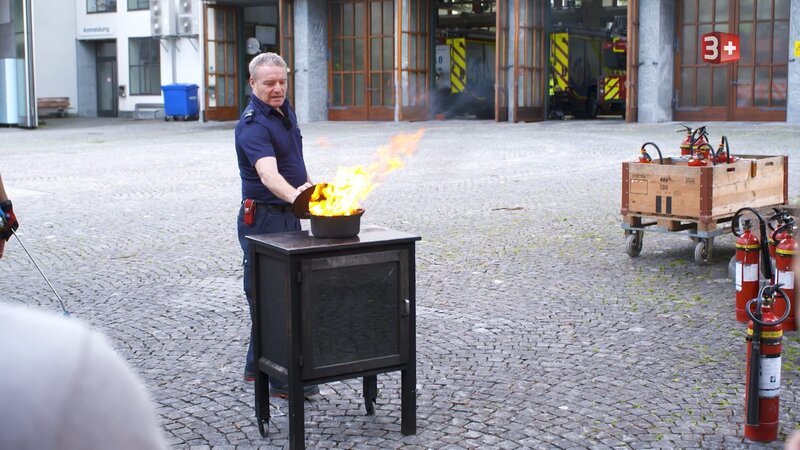 Der Polizist zeigt, wie man das Feuer löscht – Bild: CH Media