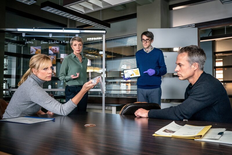 Prof. Rossi (Anna Stieblich, 2.v.l.) und Lorenz Rettig (Daniel Steiner, 2.v.r.) klären Ina Zimmermann (Melanie Marschke, l.) und Jan Maybach (Marco Girnth, r.) über die Todesursache auf. In dem Leichnam konnte Rossi einen dünnen Metallstab sicherstellen. Das Opfer starb infolge des starken Blutverlustes. – Bild: Uwe Frauendorf /​ ZDF
