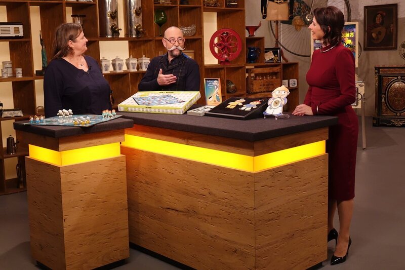 „Bares für Rares“-Moderator Horst Lichter (M.), Expertin Wendela Horz (r.) mit Gast Martina Helms (l.) und dem Brettspiel „Mainzelmännchen Konvolut“. – Bild: ZDF