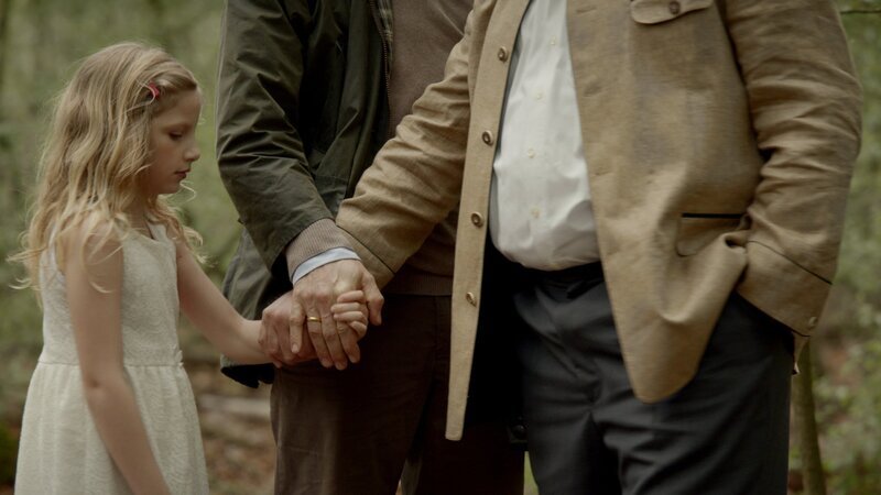Von links: Die kleine Lucy (Carlotta von Falkenhayn) wird im Wald von Kai Voss (Sebastian Hülk) an Frank Wilhelm (Michael A. Grimm) übergeben. – Bild: 3sat
