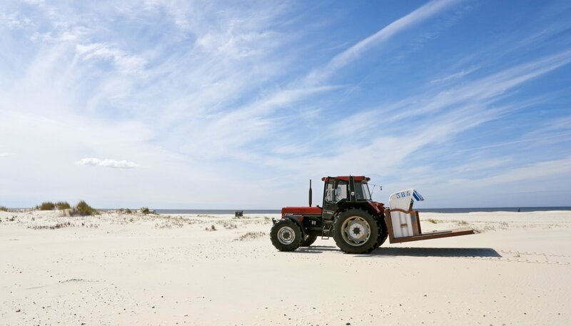 Ein Trecker, ein Strandkorb und ganz viel Sand: Nils Randow liefert Korb Nummer 584 an den Abschnitt vor der Dünenschule. – Bild: NDR /​ Julian Ringer