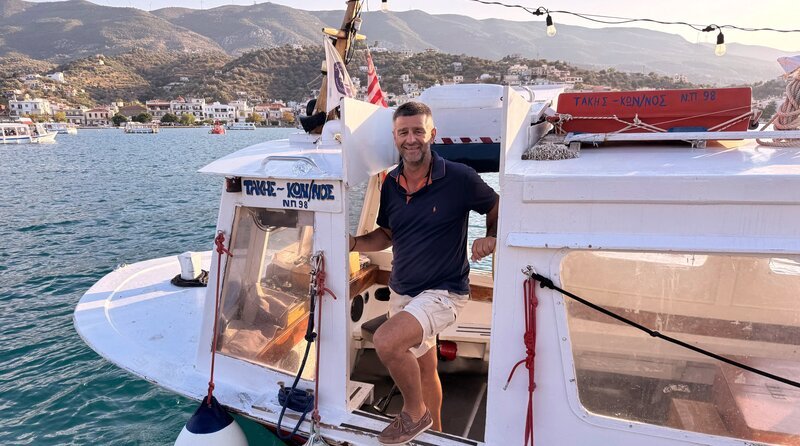 Hat sein Boot zur Mini-Fähre umgebaut: Lakis Roussos war Fischer, nun schippert er Passagiere und manchmal auch Fracht über die Meerenge zwischen der Insel Poros und dem Festland. – Bild: NDR/​Till Lehmann