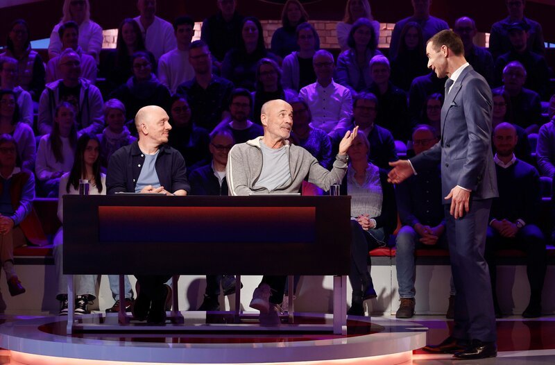 Moderator Kai Pflaume (r.) mit Rateteam-Kapitän Bernhard Hoëcker (l.) und dem Schauspieler Heiner Lauterbach (M.). – Bild: ARD/​Morris Mac Matzen