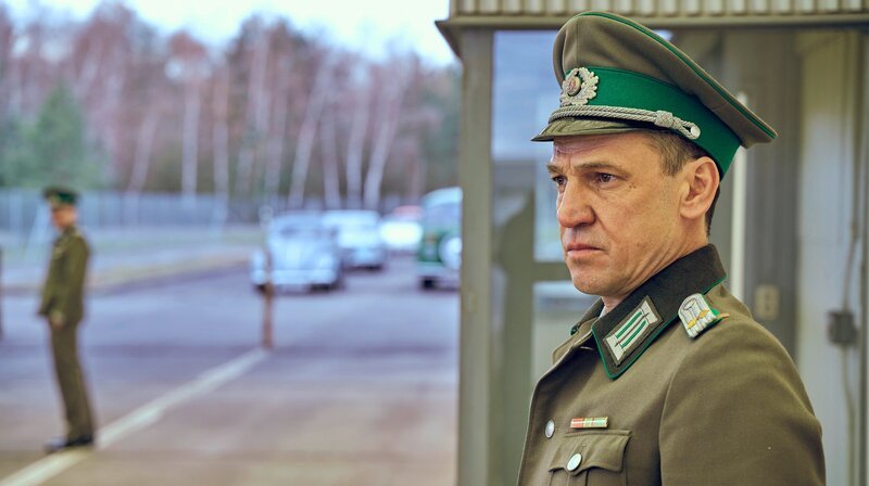 Christian Auer in der Rolle eines Stasi-Mitarbeiters bei einer Grenz-Kontrolleinheit. – Bild: NDR/​jumpmedientv GmbH/​Markus Wendler