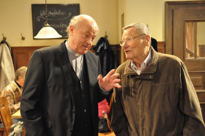 Alois verspricht sich das große Geld von der Reparatur der Lampe im Beichtstuhl. Von links: Vinzenz Kurz (Hans Stadlbauer) und Alois Preissinger (Erich Hallhuber). – Bild: BR/​Jo Bischoff