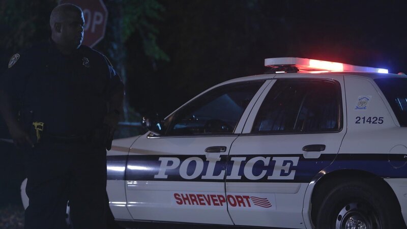 A cop stands by a cop car. – Bild: TLC