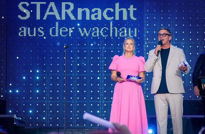 Barbara Schöneberger und Hans Sigl begrüßen nationale sowie internationale Künstlerinnen und Künstler auf der Starnacht-Bühne und verwandeln Rossatzbach in den musikalischen Hotspot der Wachau. (Motiv aus 2025) – Bild: MDR/​ipmedia/​Peter Krivograd