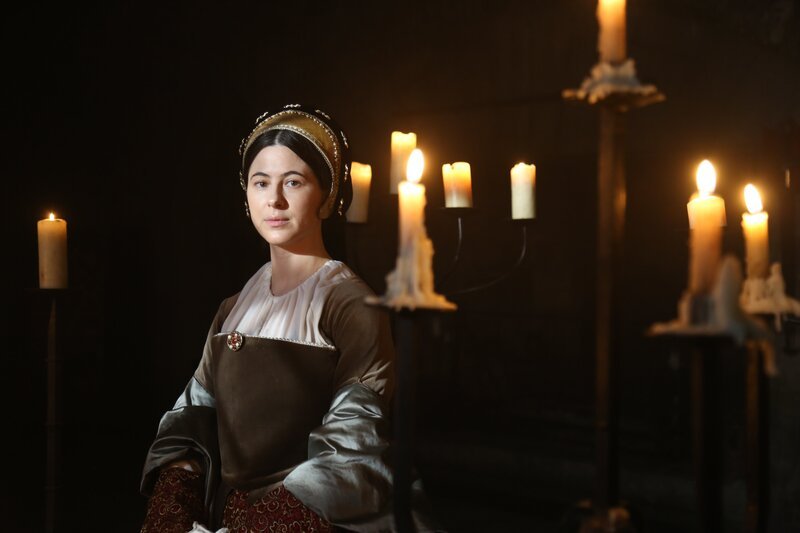 Anne Boleyn, gespielt von Aliona Baranova, steht in einem von Kerzen beleuchteten Raum. – Bild: Hit Networks Limited and Little Dot Studios/​Ashley Morris