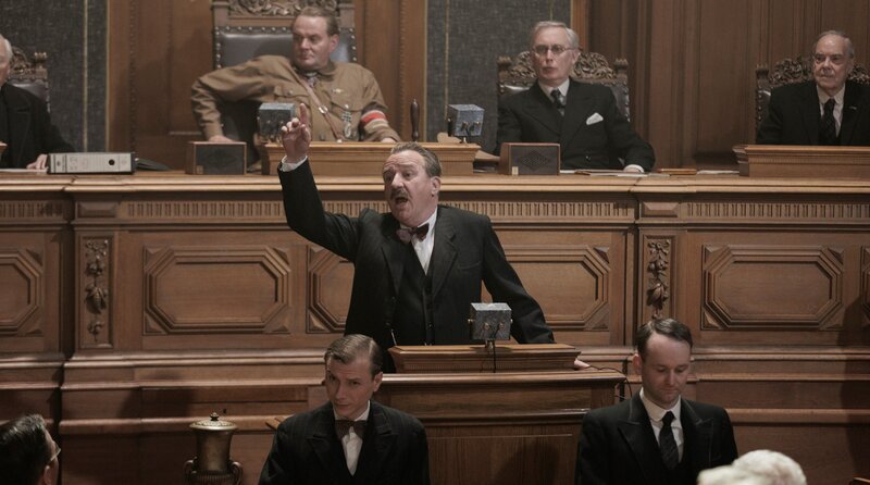Der SPD-Fraktionsleiter Otto Wels (Uwe Preuß, vorne) hält eine leidenschaftliche Rede im Plenarsaal des Reichtags, während Reichstagspräsident Hermann Göring (Devid Striesow, hinten) ihm zusieht. – Bild: Frédéric Batier/​X Filme Creative Pool/​ARD Degeto Film/​WDR/​SWR/​HR/​Radio Bremen/​Beta Film