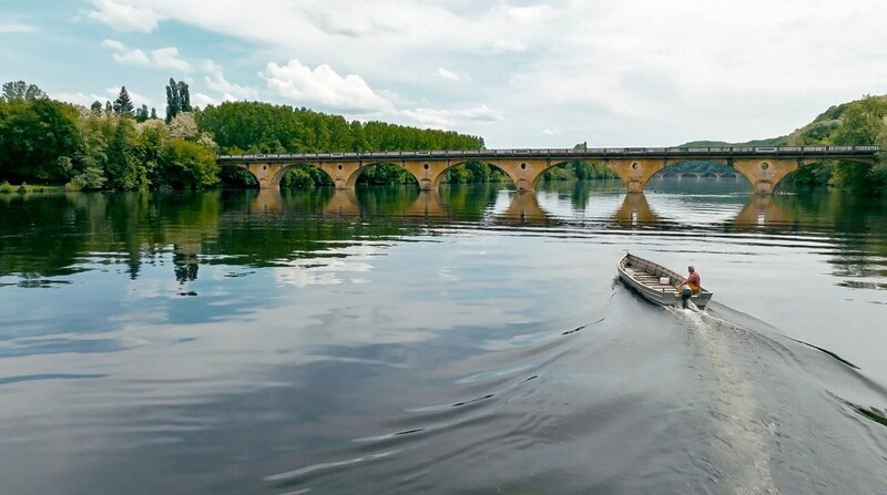 Patrick Cechetto in seinem Boot – einer der letzten Berufsfischer auf der Dordogne vor einer Bogenbrücke im Hintergrund. – Bild: 3sat