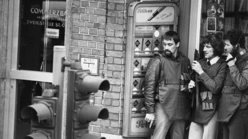 Am 18. April 1974 kommt es in der Commerzbank am Hamburger Steindamm zu einem Banküberfall mit anschließender Geiselnahme. Im Eingangsbereich des neben der Bank gelegenen Buch- und Schreibwarengeschäftes warten drei Angehörige des Mobilen Einsatzkommandos (MEK) mit Schutzwesten, Funkgerät, Pistole und Maschinenpistole auf ihren Einsatz. – Bild: ZDF