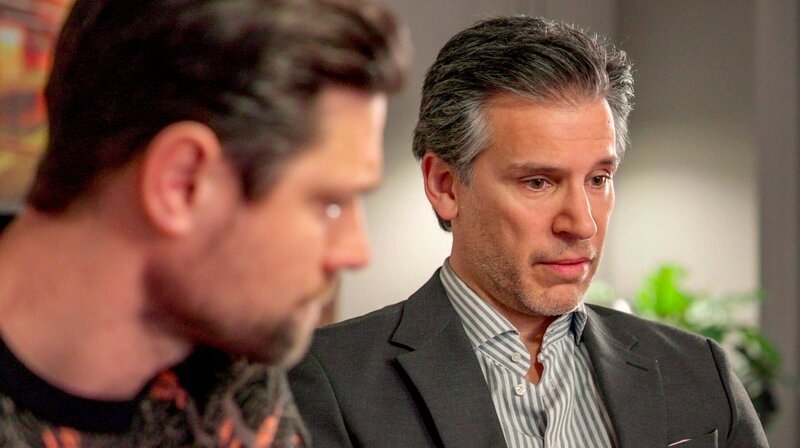 Richard (r. Florian Odendahl) erfährt, dass die EmKa Frauen systematisch schlechter bezahlt, und gibt die Information heimlich an die Presse weiter. Julius (l. Jan Stapelfeldt) steht hinter ihm. – Bild: NDR
