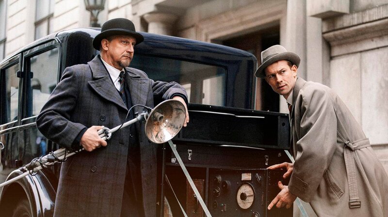 Die Kommissare Max Schreiber (Matthias Komm) und Fritz Kiehl (Christian Clauß) beim Beladen des sogenannten „Mordautos“. Im Wagen ist alles untergebracht, was die Ermittler für eine Tatortsicherung brauchen – vom Pinsel bis zur Fotoausrüstung. – Bild: phoenix/​ZDF