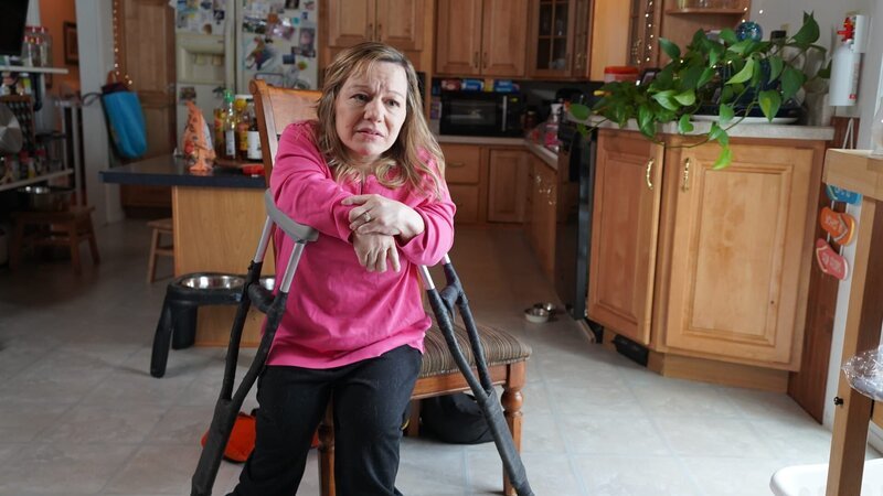 Nicole DePaul sits in a chair with her crutches during an interview – Bild: Warner Bros. Discovery