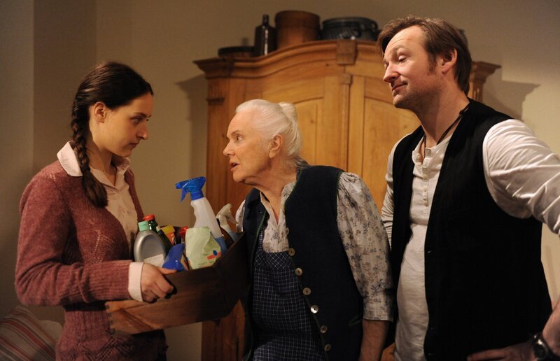 Trotz ihrer anfänglichen Zustimmung versucht Theres mit allen Mitteln, die Putzfrau bloßzustellen. Von links: Tamar (Irina Kurbanova), Theresa Brunner (Ursula Erber) und Gregor Brunner (Holger M. Wilhelm). – Bild: BR/​Marco Orlando Pichler