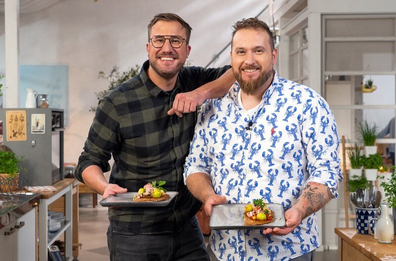 Sören Anders (li.) und Frédéric Morel haben, aus den übrig gebliebenen Zutaten, eine Tortilla – natürlich aus Buchweizenmehl – mit Käse und Zwiebeln kreiert. Belegt mit Rosenkohl, Tomatensauce, Kasseler und Kräutertopping. – Bild: SWR/​2 Bild GmbH