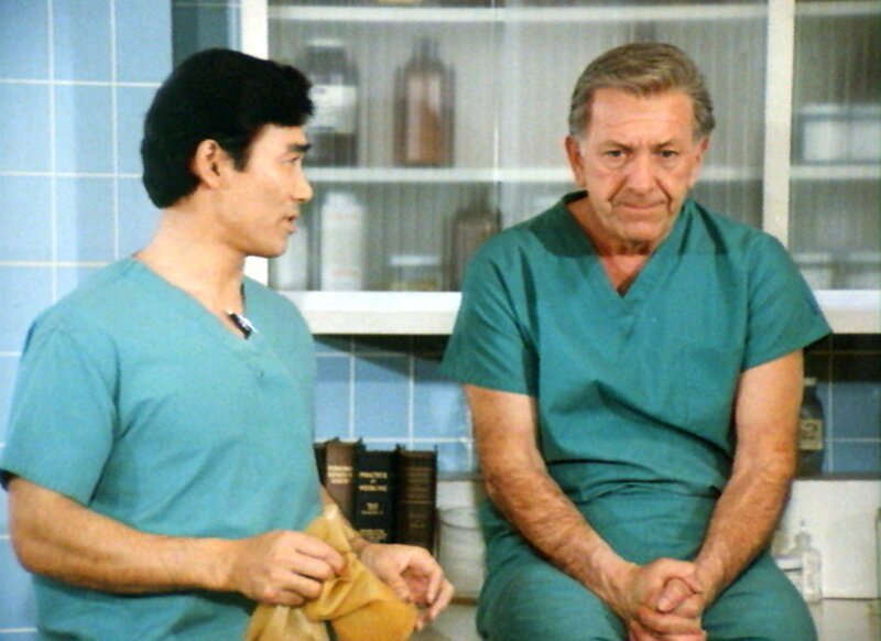 Quincy (Jack Klugman) droht seinen Ruf zu verlieren. Sam (Robert Ito, li.) will ihm helfen, seine Glaubwürdigkeit wiederherzustellen. – Bild: RTPL /​ RTLplus