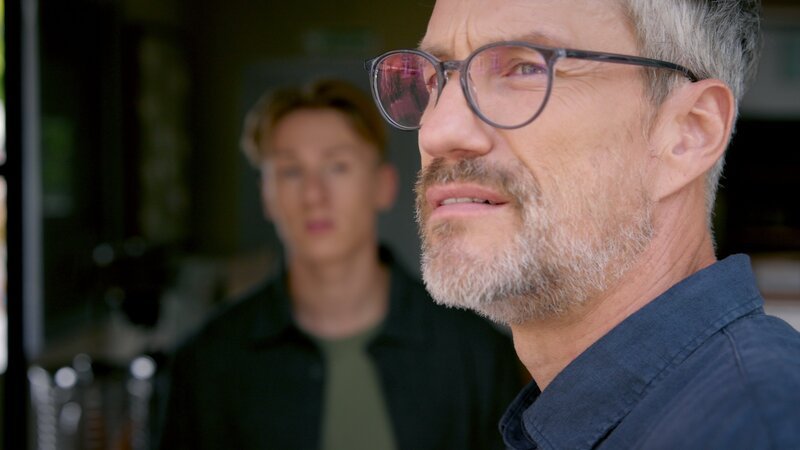 Henning (Stefan Bockelmann) gesteht Lennox (Leif Lunburg, hinten), dass er gerne viel mehr Zeit mit Romy verbringen würde. – Bild: RTL /​ Der charmante Fremde