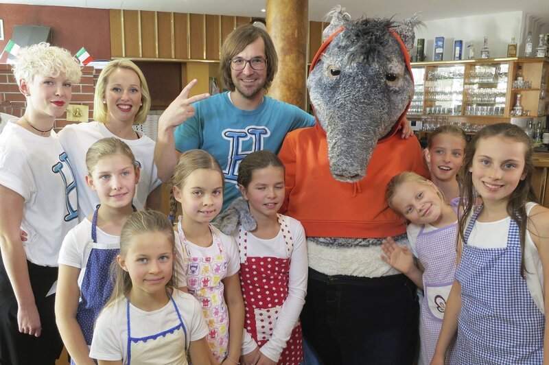 Angelockt von einer fröhlichen, italienischen Tarantella wippt und wiegt sich der TanzTapir in eine Pizzeria. Singa, Herr H mit „Pizza Margherita“ und die TanzAlarm-Kids mit „Basta ich will Pasta“ finden dann das richtige Rezept für einen leckeren und bewegten Pizzeria-Besuch. – Bild: KiKA/​MingaMedia