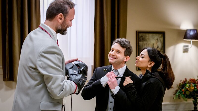 Fritz (Thimo Meitner m.) und Lale (Yeliz Simsek r.) freuen sich, dass der Portier (Komparse, l.) bestätigt, dass es Abraxas gut geht. – Bild: ARD/​WDR/​Christof Arnold