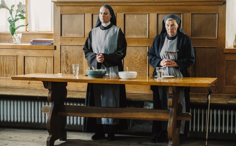 Schwester Barbara (Corinna Harfouch, links) und Schwester Julia (Christiane Blumhoff, rechts) betend im Speisesaal des Nonnenklosters. – Bild: BR/​Roxy Film GmbH/​Hendrik Heiden