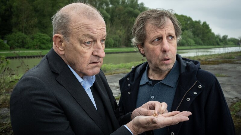 Privatdetektiv Georg Wilsberg (Leonard Lansink, l.) zeigt Ekki Talkötter (Oliver Korittke, r.) einen wichtigen Fund – führt die Goldkette zur Lösung des Rätsels um den verschwundenen Bräutigam? – Bild: ZDF