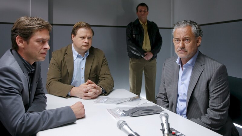 Die Cops Christian Lind (Tom Mikulla, l.), Tobias Hartl (Michael A. Grimm, 2.v.l.) zweifeln an der Glaubwürdigkeit des EU-Abgeordneten Eckart König (Rolf Kanies, r.). Polizist im Hintergrund: Komparse. – Bild: ZDF