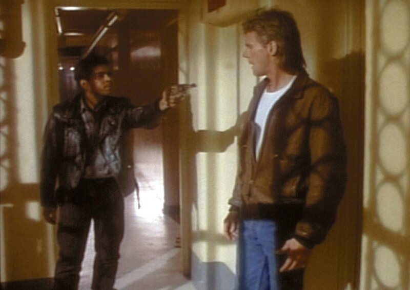Der Drogenhändler Spider (Ramon Franco, l.) bedroht MacGyver (Richard Dean Anderson, r.) mit einer Waffe. – Bild: Paramount Pictures