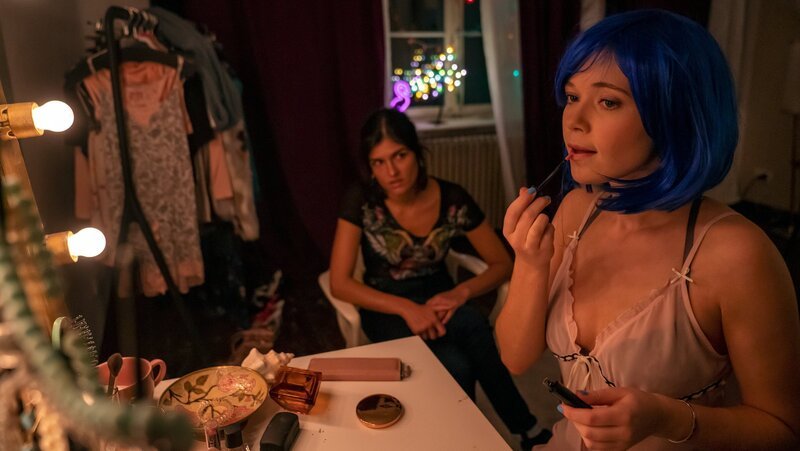 Während Fiona (Farina Flebbe, r.) sich für ihren Auftritt als Camgirl „Kleine Blume“ zurechtmacht, erzählt sie ihrer Freundin Lina (Julie Burkardt, l.), dass sie sich nicht so ohne weiteres von ihrem Freund trennen könne – sie schulde ihm noch einen Gefallen. – Bild: ZDF