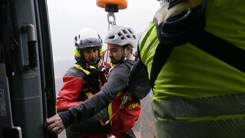 Bergung aus der Luft: Ein Notarzt zieht den geretteten Patienten an der Seilwinde in den Hubschrauber. – Bild: ZDF
