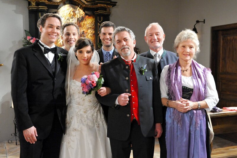 Das Hochzeitspaar Xaver (Jan van Weyde, l.) und Kira (Mareike Lindenmeyer, 2.v.l.) stellen sich mit Martin (David Paryla, 2.v.l.), Nils (Florian Stadler, 4.v.l.), Julius (Michele Oliveri, 3.v.r.), Alfons (Sepp Schauer, 2.v.r.) und Hildegard (Antje Hagen, r.) zum Hochzeitsfoto auf. – Bild: ARD/​Ann Paur