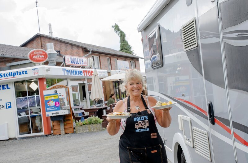 Carola „Rolly“ Roßberg vor ihrem Trucker-Imbiss. Mitten im Wendland, direkt an der B216, ist der kleine Imbiss für viele ein Stück Heimat – mit Gerichten, die sie an ihre Oma erinnern, wie Sauerfleisch oder Senfeier. – Bild: NDR/​Flemming Filmproduktion GmbH/​Nele Martensen