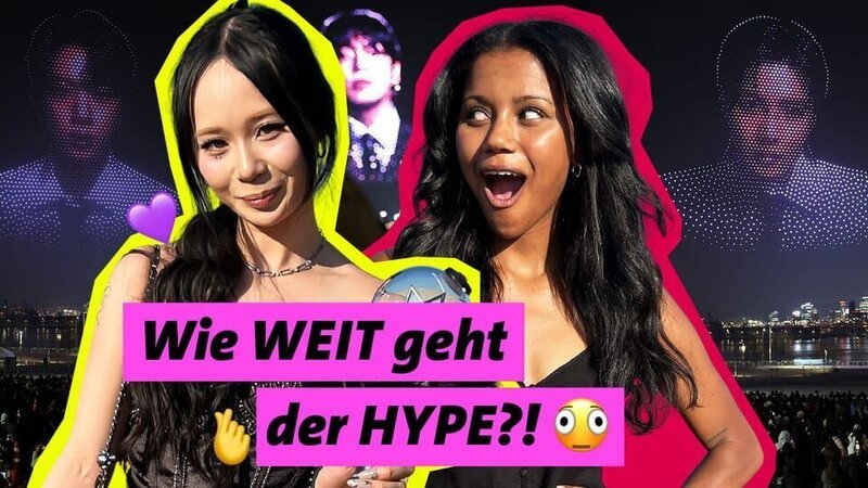 K-Pop Fan Thana (links) und POV-Host Kiara posieren gut gelaunt vor dem BTS-Konzert. Mit Lightstick und passendem Fan-Outfit zeigt Thana ihre Begeisterung für K-Pop und ist so Teil einer Community, die Fans auf der ganzen Welt verbindet. – Bild: WDR/​WeAreEra