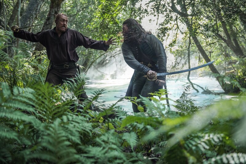 Silver (Luke Arnold, r.), Hands und einige Piraten verfolgen Flint (Toby Stephens, l.) und Dooley, die den Schatz nach Skeleton Island gebracht haben. Werden sie es schaffen, ihn zu vergraben, bevor ihre Feinde ihn in ihre Gewalt bringen können? – Bild: Starz Entertainment, LLC /​ David Bloomer