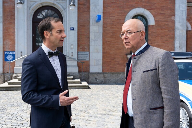 Kulturdezernent Dr. Baumgartner (Oliver Bürgin, l.) hofft, dass Polizeidirektor Achtziger (Alexander Duda, r.) eine passende Geschenkidee für die Abendveranstaltung hat, zu der sie geladen sind. – Bild: ORF/​ZDF/​Linda Gschwentner