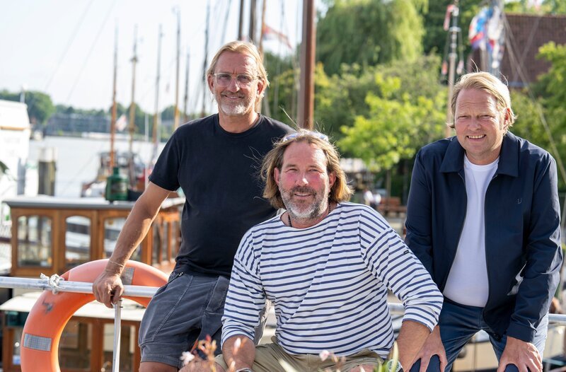 Die beiden Spitzenköche Björn Freitag (r) und Frank Buchholz (l) reisen in die nordwestlichste Ecke Deutschlands. Am Steuer des Hausboots steht wieder Skipper Kai Linnenbrügger (M). – Bild: WDR/​Melanie Grande