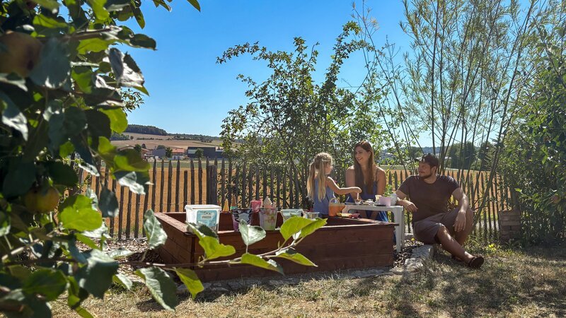 Juliane (34) (M.) mit Tochter Leni (l.) und ihrem Mann Christoph (r.) beim Spielen am Hochbeet. – Bild: ZDF und KunamoFilm, Simone Matheis