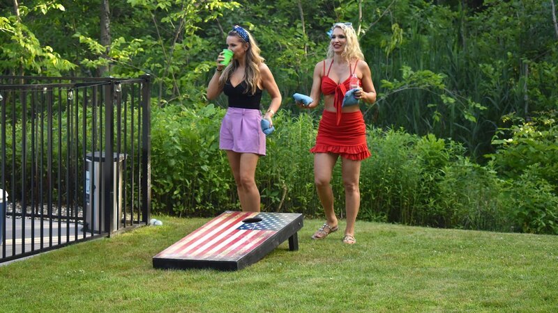 Vanja Grbic smiles and prepares to throw a cornhole bag while Sanela sips her drink in her backyard. – Bild: TLC (DEUT)