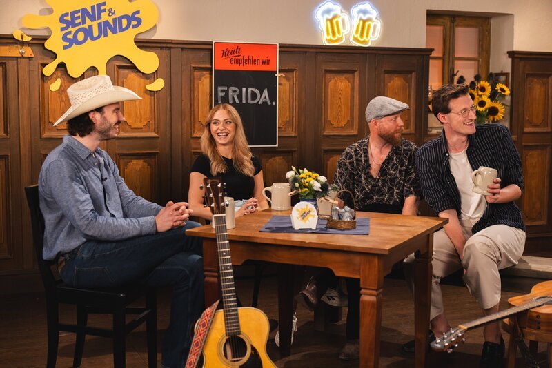 Mundart-Pop, Brass oder Volksmusik – der junge Sound aus Bayern wird gehört und gefeiert. Bei einem Wirtshaus-Quiz mit Stammtisch-Vibes nehmen die Hosts Alina Khani (2. von rechts), Noah Hansen und Marcel Ertl Stars und Newcomer dieser bayerischen Musikszene genauer unter die Lupe. Was dabei nicht fehlen darf: Musikalische Acts, Schlagfertigkeit und jede Menge Spaß. – Bild: Leah Ruprecht /​ BR