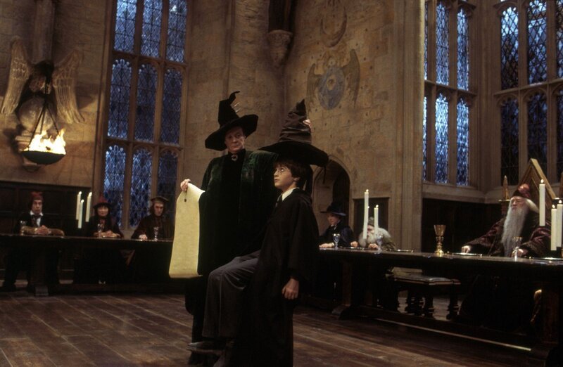 Am ersten Tag in der Zauberschule Hogwarts werden Schüler von einem sprechenden Zauberhut auf vier Häuser verteilt. Professor McGonagall (Maggie Smith, l.) setzt Harry Potter (Daniel Radcliffe) auf den Stuhl und setzt ihm einen Hut auf. Harry hofft, im gleichen Haus unterzukommen wie seine Freunde. – Bild: VOX/​Warner Bros. Ent.